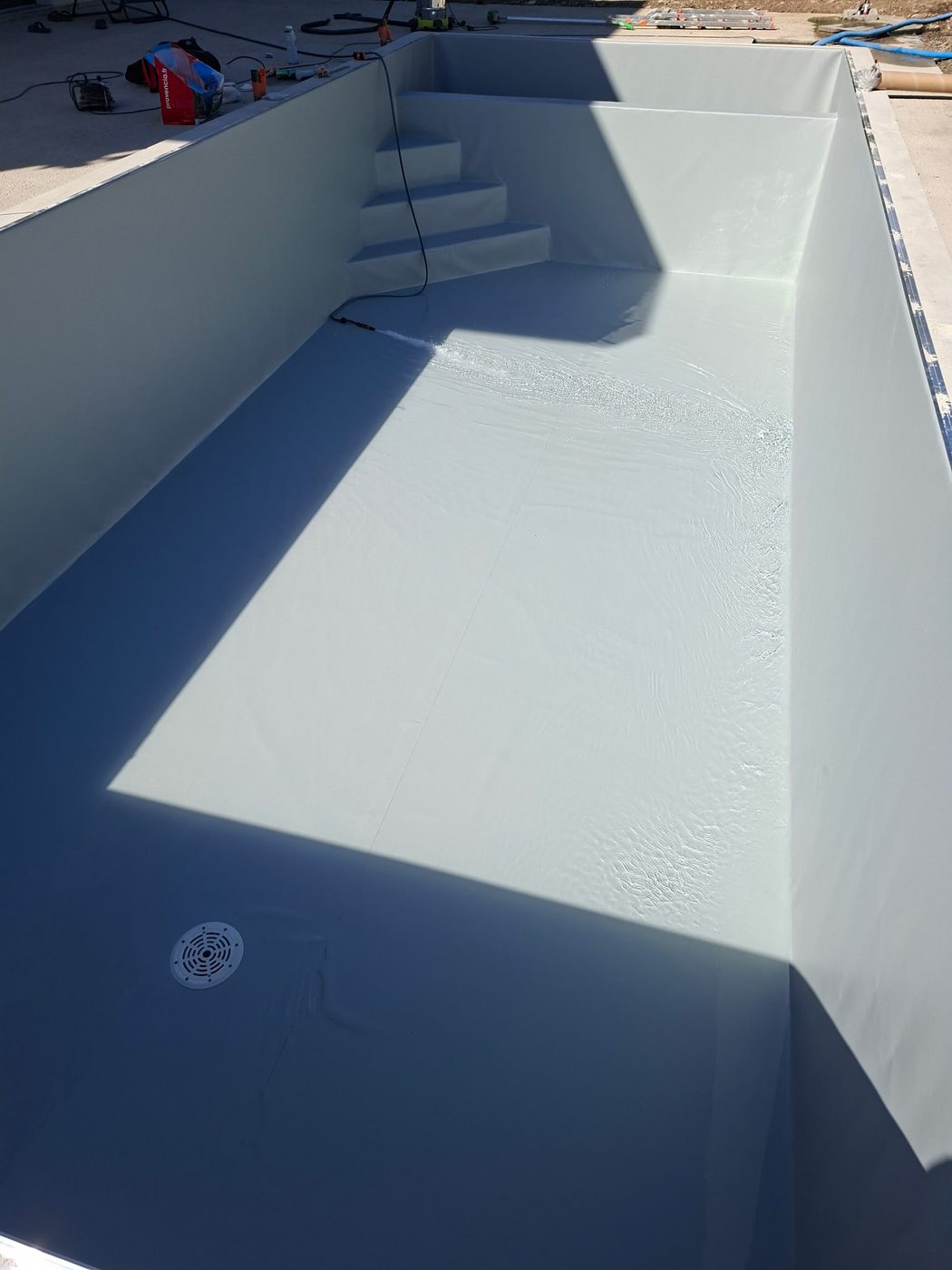 Liner gris clair posé, mise en eau de la piscine en cours